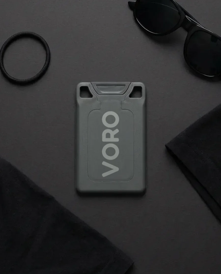 The charcoal VORO card on a charcoal field with sunglasses, a hair tie, and a black tee.