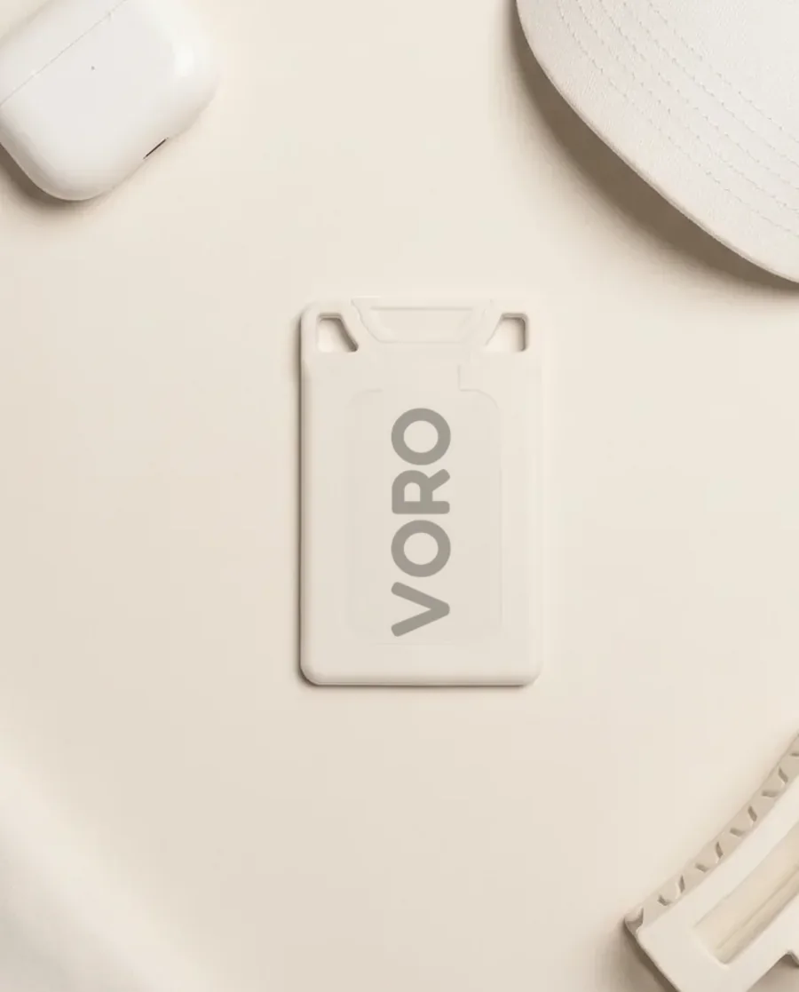 The white VORO card on a warm white field with earbuds, a cap, and a claw clip.