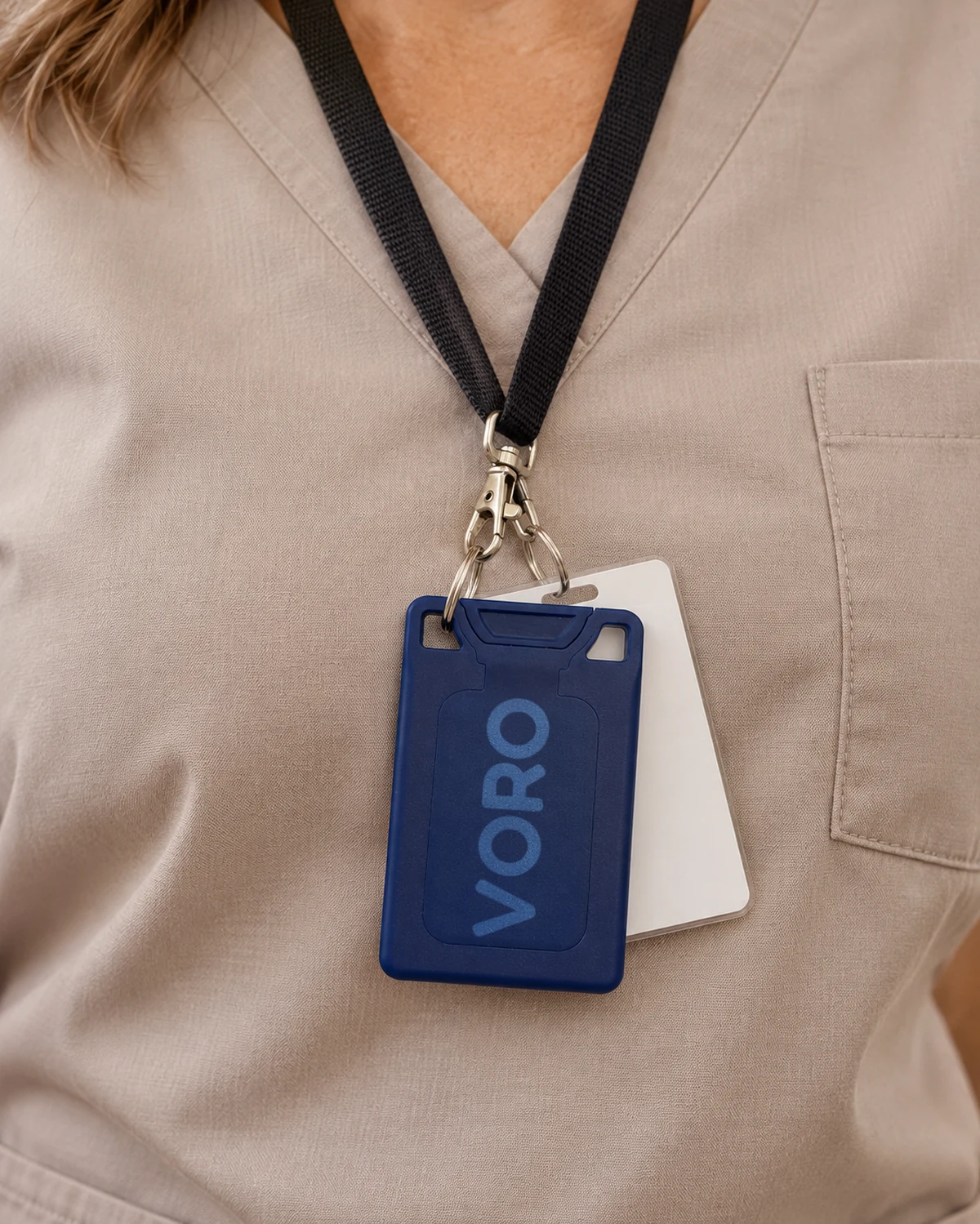 The navy VORO card attached through a corner slot to a work lanyard, beside a separate ID badge.