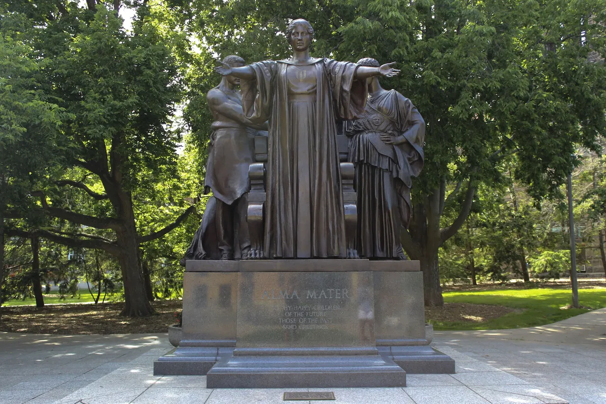The Alma Mater statue on the University of Illinois campus, framed by summer trees.
