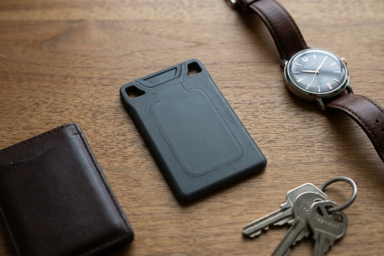 A charcoal VORO lying flat on a desk next to a watch, wallet, and keys.